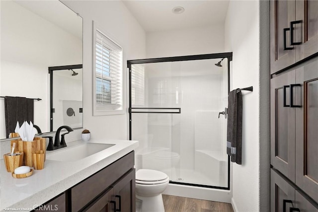 bathroom featuring toilet, vanity, wood-type flooring, and walk in shower