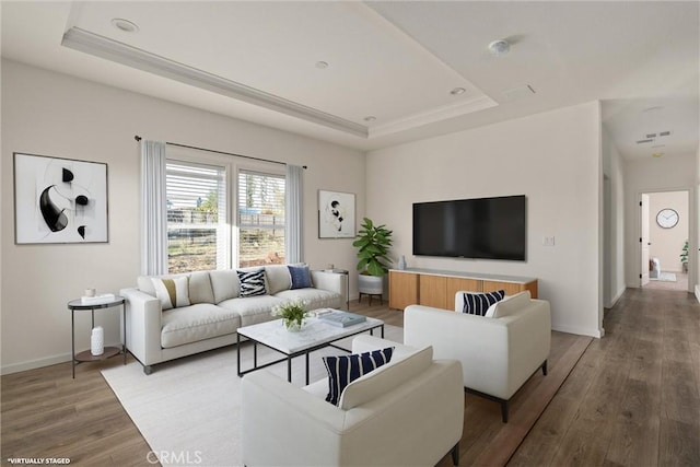 living room with wood-type flooring and a tray ceiling