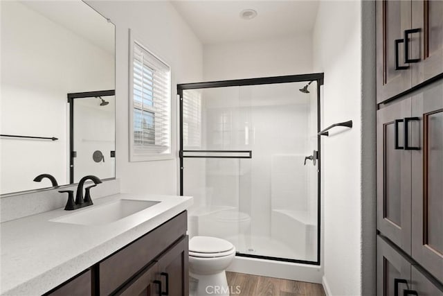 bathroom with hardwood / wood-style floors, vanity, toilet, and a shower with shower door