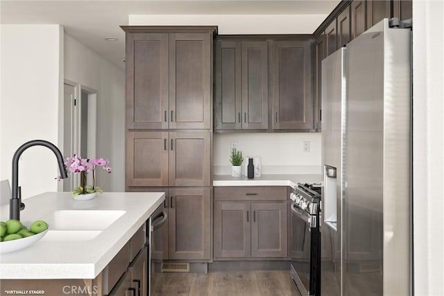 kitchen with hardwood / wood-style flooring, sink, dark brown cabinets, and appliances with stainless steel finishes