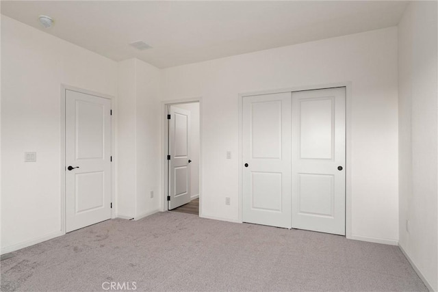 unfurnished bedroom featuring a closet and light colored carpet