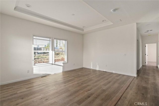 spare room with dark hardwood / wood-style flooring and a raised ceiling