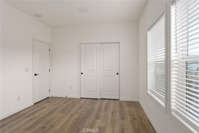 unfurnished bedroom with a closet and dark wood-type flooring