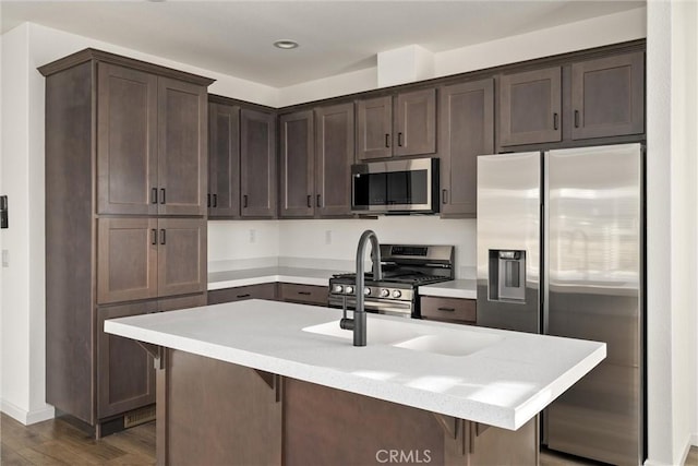 kitchen with dark hardwood / wood-style floors, a kitchen breakfast bar, dark brown cabinets, and appliances with stainless steel finishes