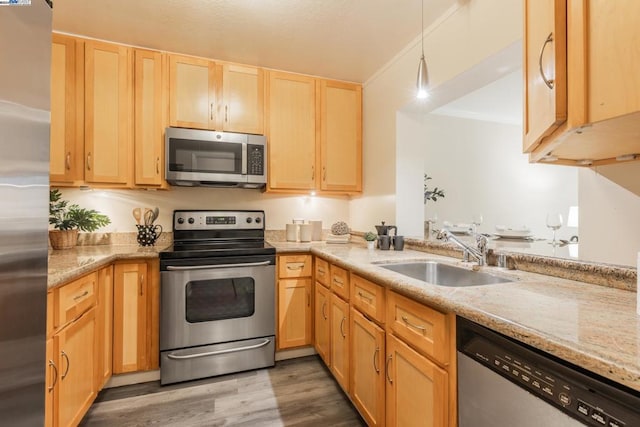 kitchen featuring hanging light fixtures, sink, light wood-type flooring, appliances with stainless steel finishes, and kitchen peninsula