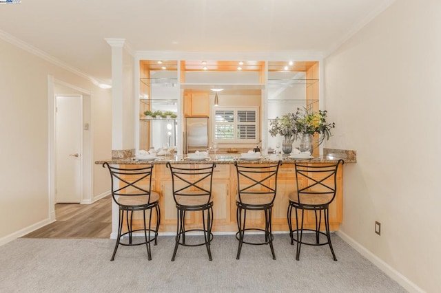 bar featuring light stone counters, light brown cabinets, light colored carpet, and crown molding