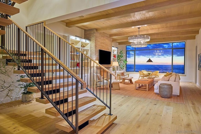 stairs with wooden ceiling, beam ceiling, hardwood / wood-style flooring, and a notable chandelier