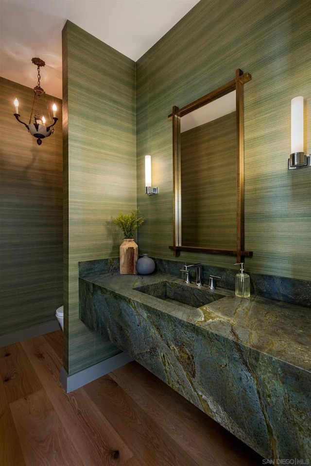 bathroom with sink, wood-type flooring, a notable chandelier, and toilet