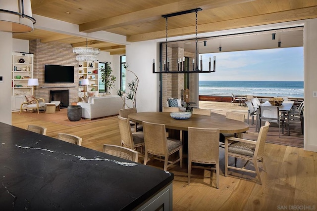 dining space featuring hardwood / wood-style flooring, a notable chandelier, a water view, and a view of the beach