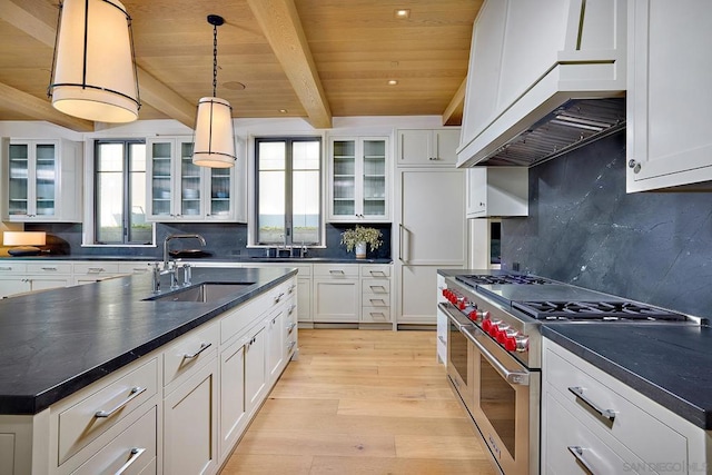 kitchen featuring double oven range, sink, decorative light fixtures, beam ceiling, and custom range hood