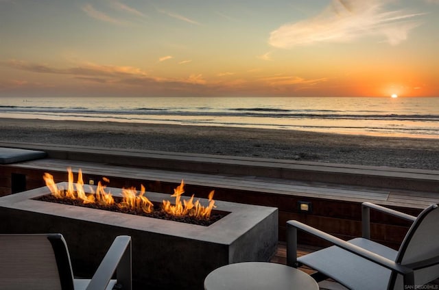 exterior space featuring a water view, a beach view, and an outdoor fire pit