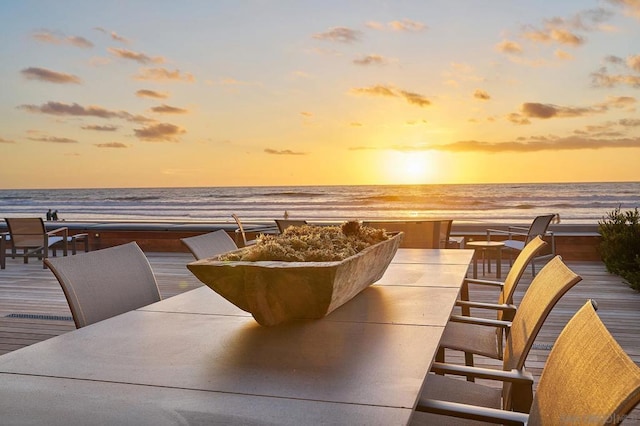 patio terrace at dusk featuring a water view and a beach view