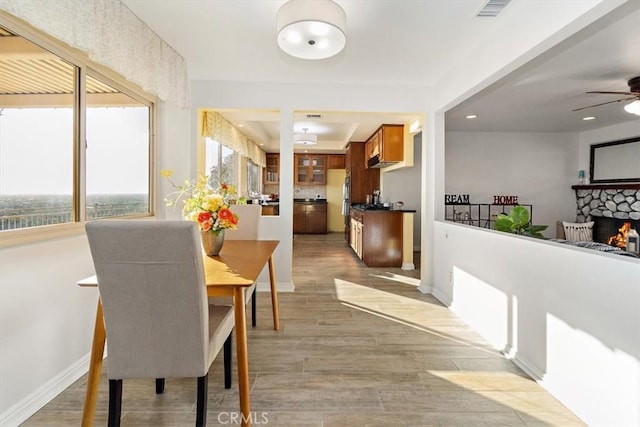 dining area with ceiling fan, a fireplace, and light hardwood / wood-style flooring