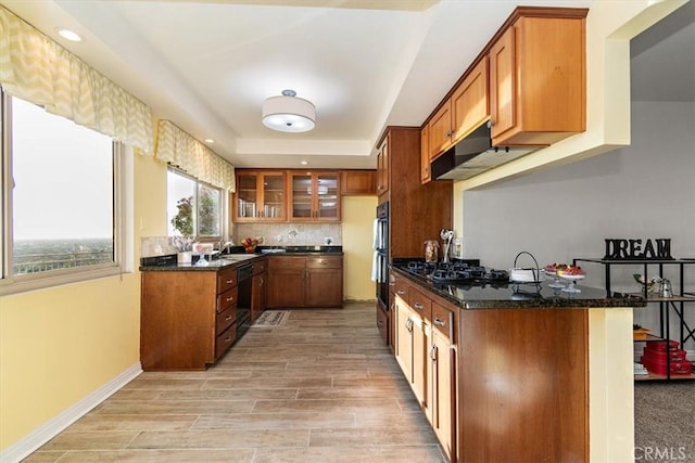 kitchen featuring kitchen peninsula, sink, dark stone countertops, light hardwood / wood-style floors, and black appliances