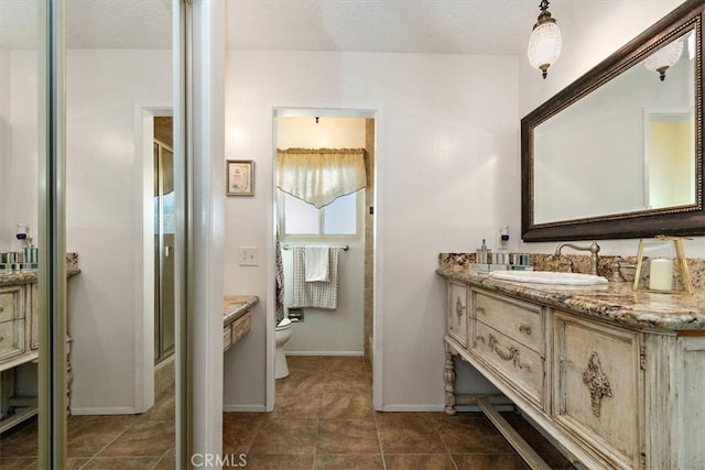 bathroom featuring vanity, toilet, a shower with door, and a textured ceiling