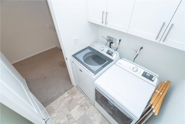 clothes washing area featuring washing machine and dryer and cabinets