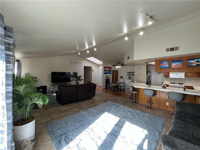 living room with track lighting, a textured ceiling, vaulted ceiling, ceiling fan, and tile patterned flooring