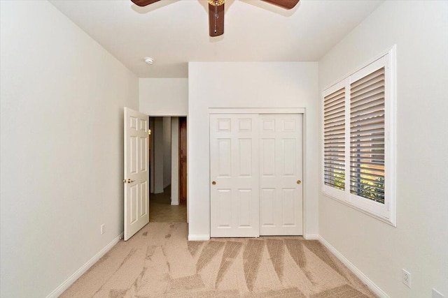 unfurnished bedroom featuring light carpet, a closet, and ceiling fan