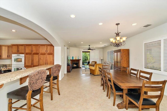 tiled dining area with ceiling fan with notable chandelier