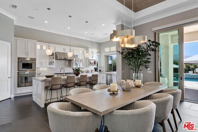 dining space featuring dark parquet floors, ornamental molding, and sink