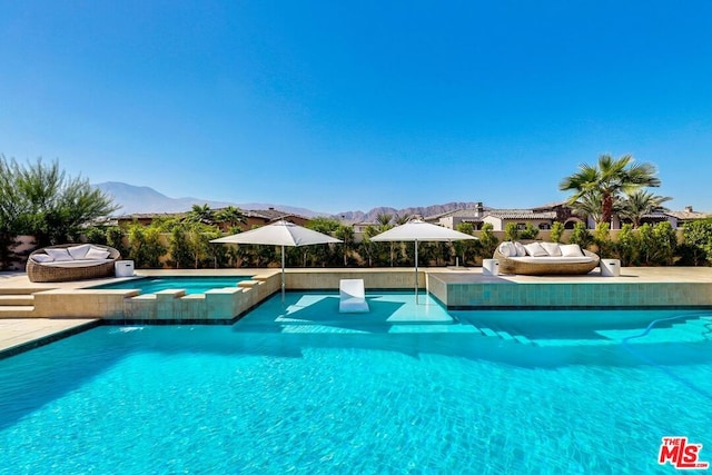 view of pool with a mountain view, pool water feature, and an in ground hot tub