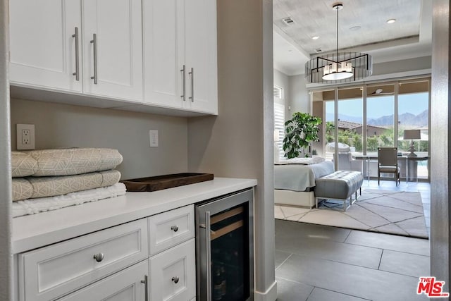 bar featuring pendant lighting, a mountain view, white cabinets, wine cooler, and light tile patterned floors