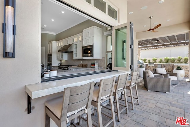 kitchen featuring a kitchen breakfast bar, tasteful backsplash, white cabinetry, kitchen peninsula, and stainless steel appliances