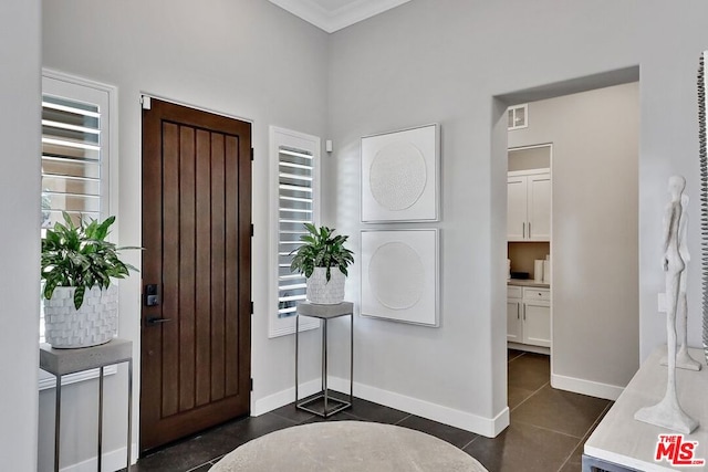 tiled entrance foyer featuring crown molding and a healthy amount of sunlight