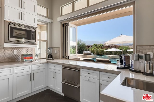 kitchen with a mountain view, decorative backsplash, white cabinetry, and stainless steel microwave