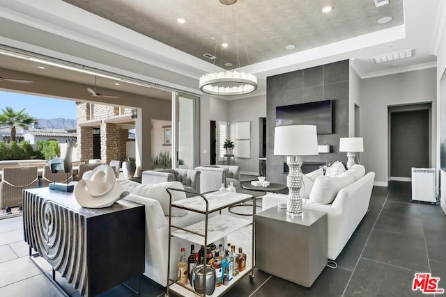 living room featuring an inviting chandelier, dark tile patterned floors, crown molding, and a tray ceiling