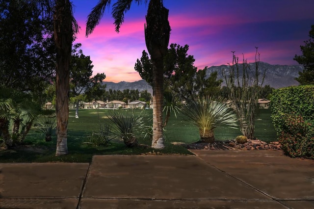 patio terrace at dusk featuring a lawn and a mountain view