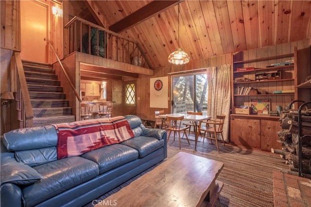 living room with stairs, beam ceiling, wood ceiling, and wooden walls