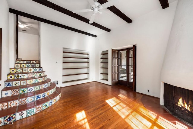 unfurnished living room featuring hardwood / wood-style flooring, ceiling fan, beamed ceiling, and french doors