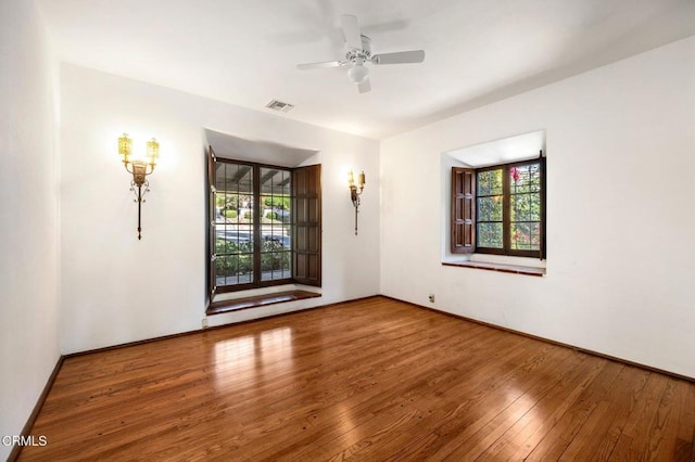 spare room with hardwood / wood-style floors, a wealth of natural light, and ceiling fan