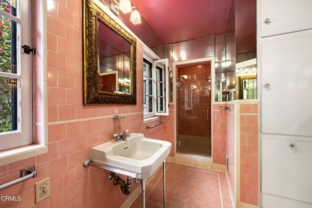 bathroom with tile patterned flooring, a shower with shower door, and tile walls