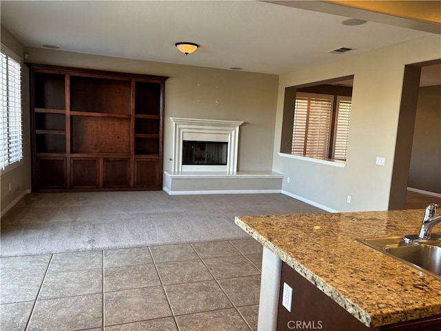 unfurnished living room featuring light colored carpet and sink