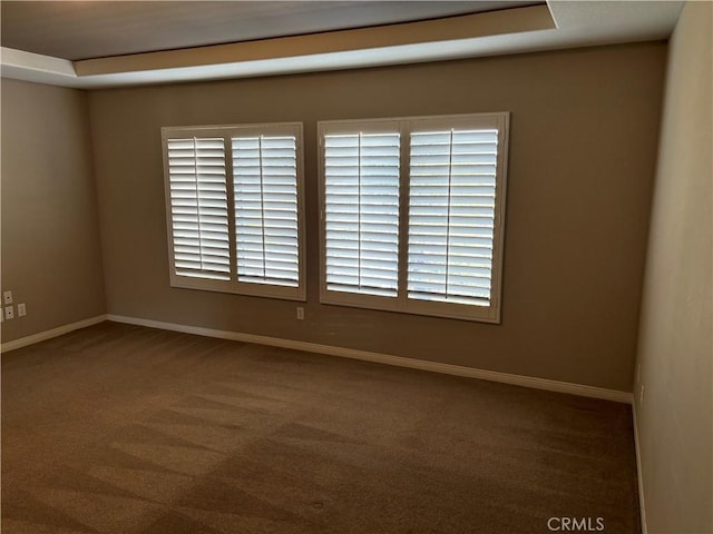 carpeted empty room featuring a tray ceiling