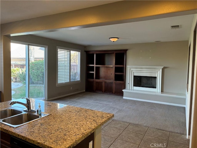 kitchen with light carpet, sink, and light stone countertops