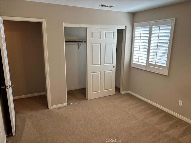 unfurnished bedroom with light colored carpet and a closet