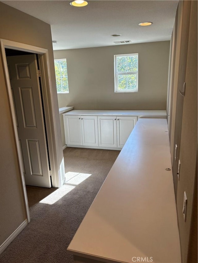 hallway featuring light colored carpet and plenty of natural light