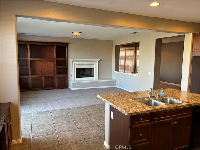 kitchen featuring light carpet, a center island with sink, sink, light stone countertops, and black dishwasher