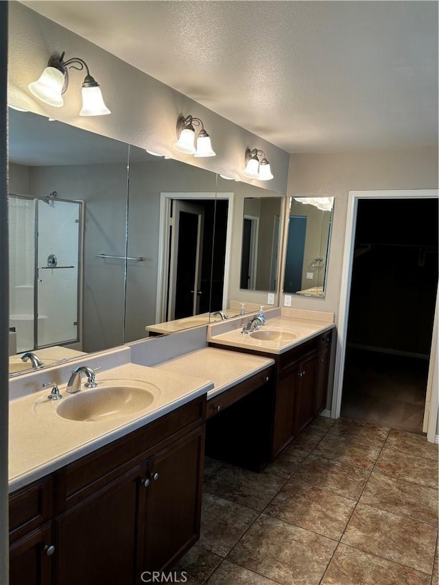 bathroom featuring tile patterned flooring, vanity, a shower with shower door, and a textured ceiling