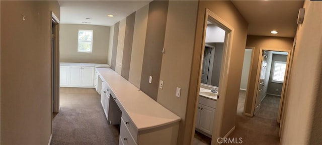 corridor featuring light colored carpet and sink