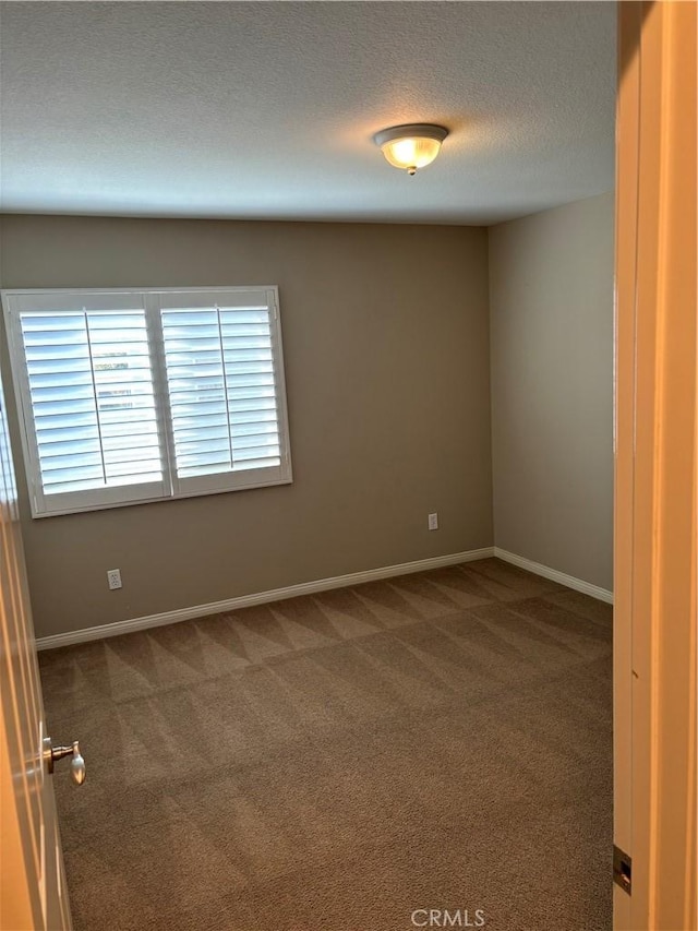 empty room with a textured ceiling and dark carpet