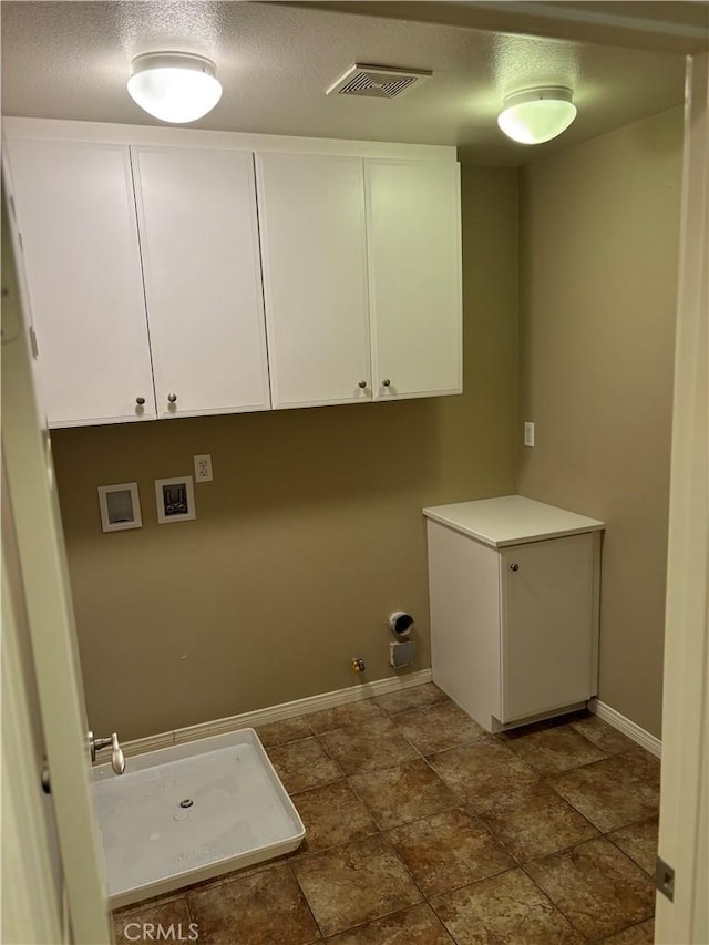 washroom with cabinets, hookup for a washing machine, a textured ceiling, and hookup for a gas dryer