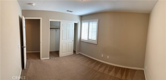 unfurnished bedroom featuring carpet flooring, vaulted ceiling, and a closet