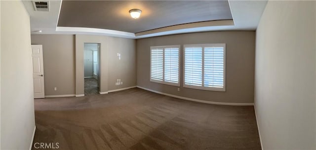 unfurnished room with a tray ceiling and dark carpet