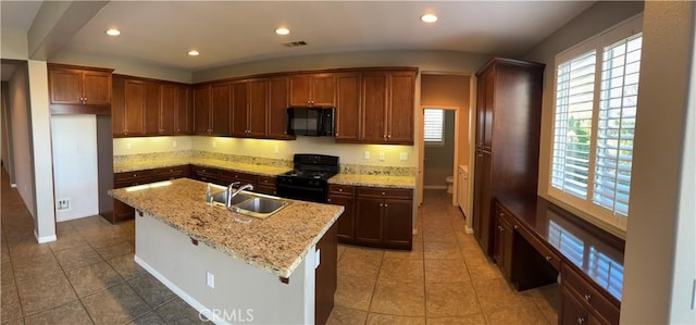 kitchen featuring light stone countertops, sink, tile patterned flooring, a center island with sink, and black appliances