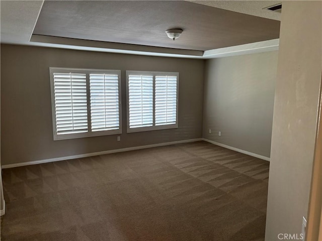 carpeted empty room featuring a tray ceiling and a textured ceiling