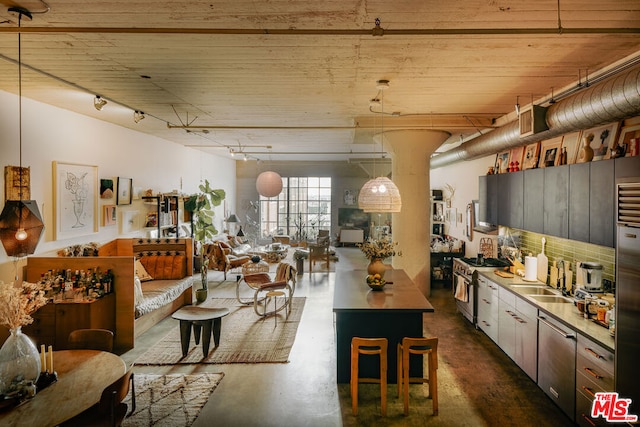 kitchen with hanging light fixtures, appliances with stainless steel finishes, sink, and a center island